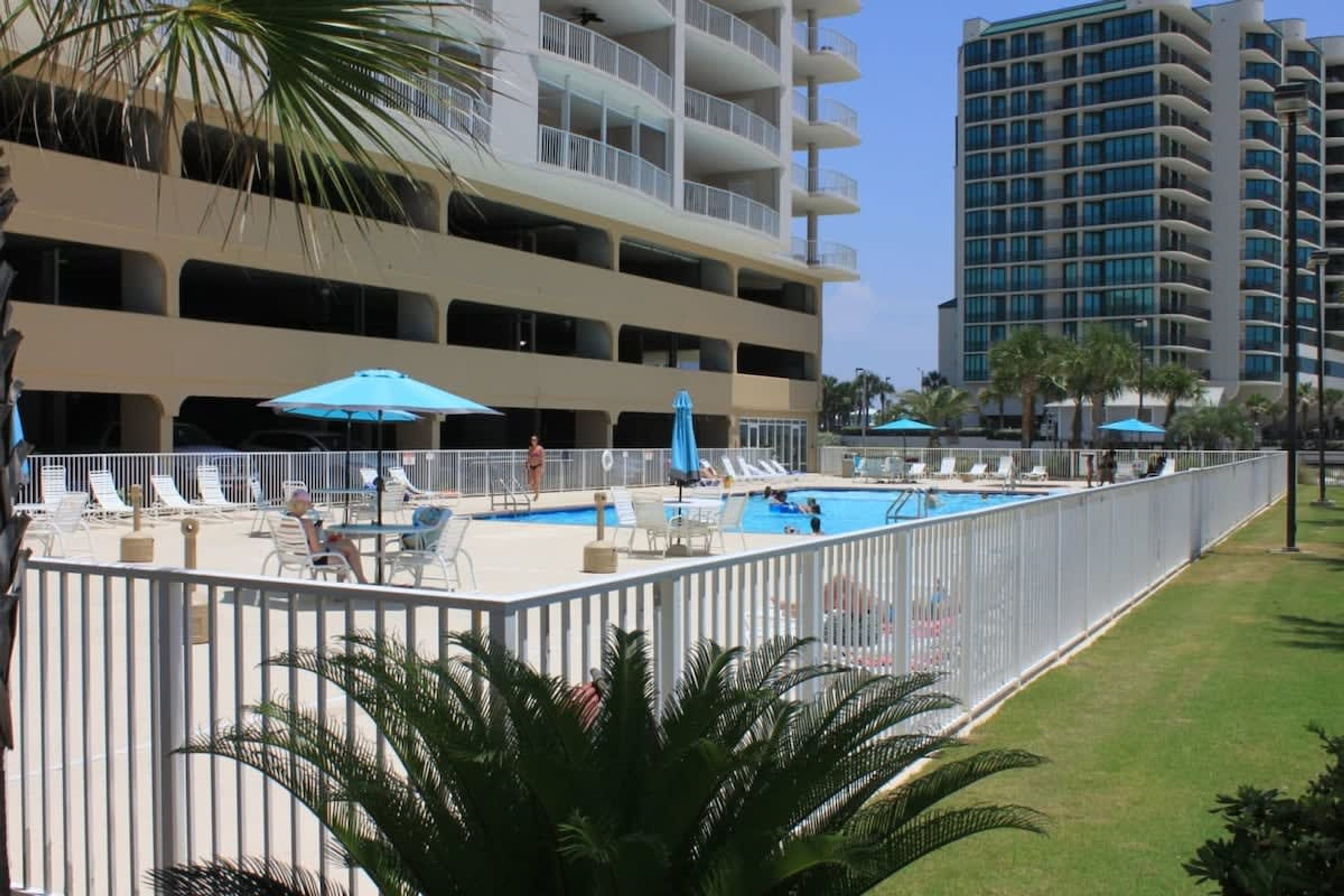 A hotel with a pool area, multiple balconies, and a view of a tall building.