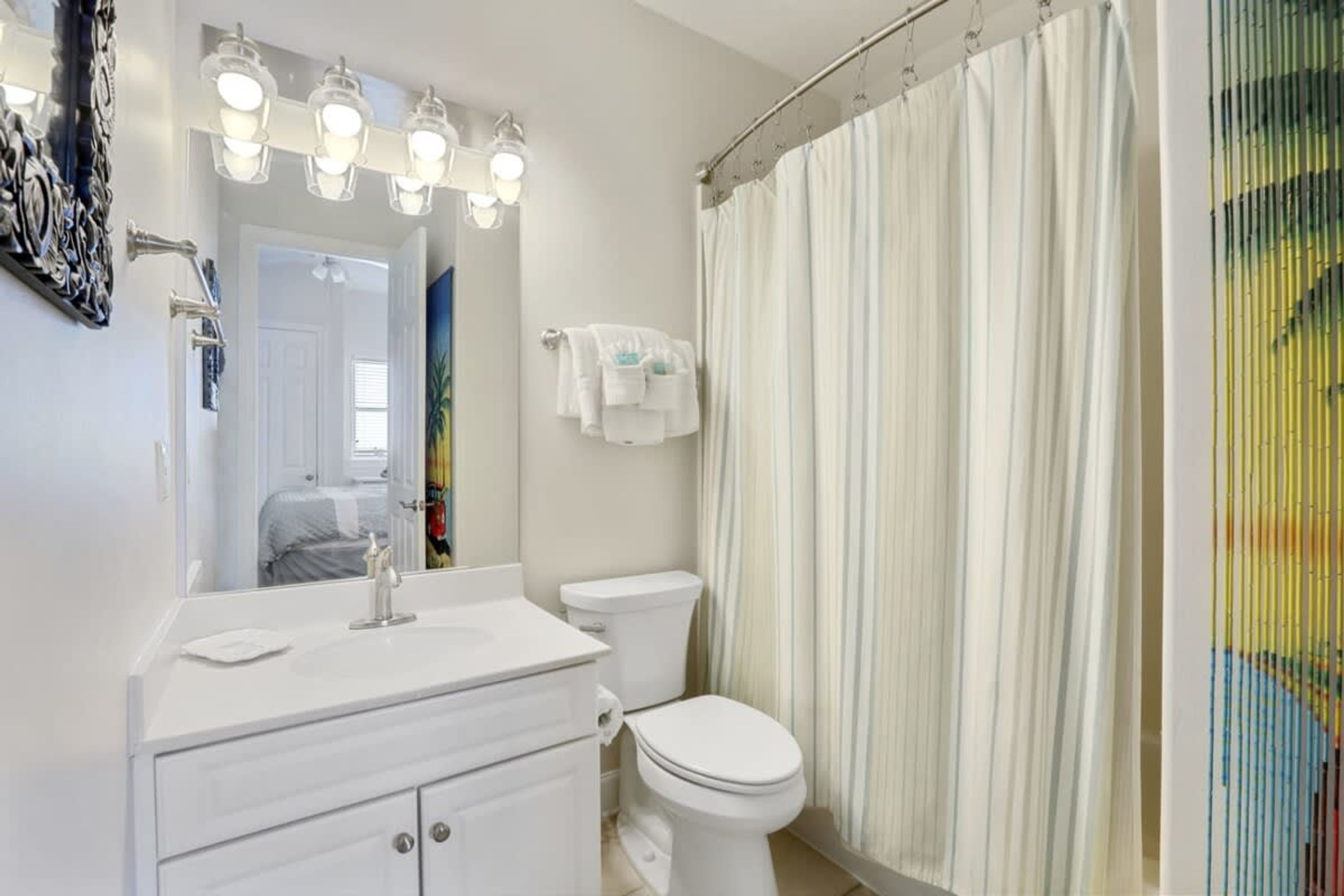 Un baño con tocador blanco, inodoro y cortina de ducha.
