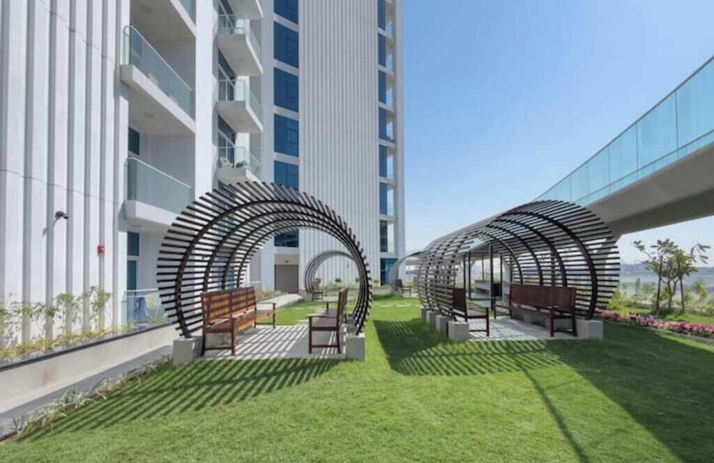 Un espacio exterior moderno con dos estructuras circulares, bancos y un césped.