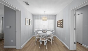 A dining area with a round table and chairs, a chandelier, and framed artwork on the walls. - Marvelous 3-bedroom house with AC in charming Palm Harbor/ Ozona (Palm Harbor)
