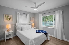 A bedroom with a bed, nightstands, a ceiling fan, and a window with curtains. - Marvelous 3-bedroom house with AC in charming Palm Harbor/ Ozona (Palm Harbor)