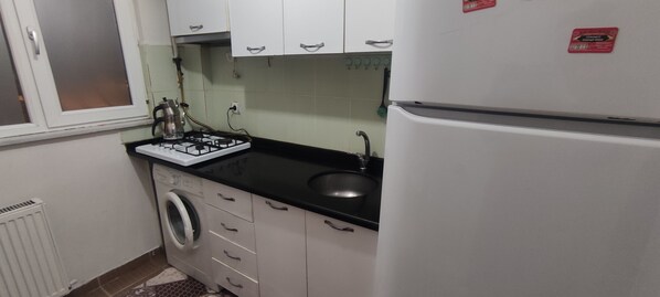A compact kitchen with a gas stove, sink, and a refrigerator.
