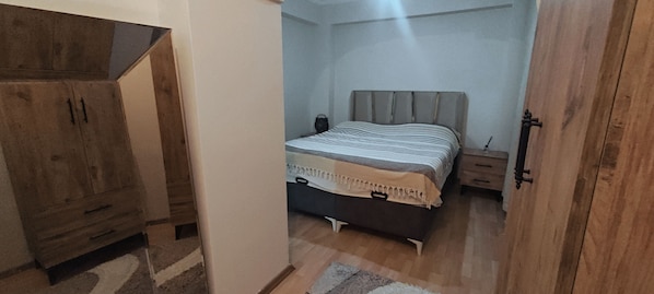 A bedroom with a bed, nightstand, and wooden wardrobe.