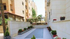A courtyard with a central paved area surrounded by low walls, potted plants, and flower boxes. - 7th Circle Diamnod (Amman)