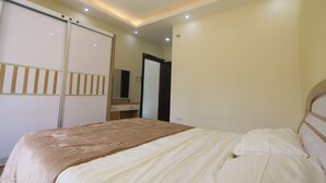 A bedroom with a bed, a wardrobe, a mirror, and recessed ceiling lights. - 7th Circle Diamnod (Amman)