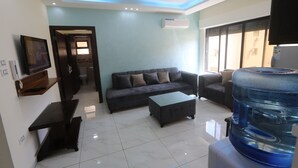 A modern living room with a sofa, coffee table, and a water dispenser. - 7th Circle Diamnod (Amman)