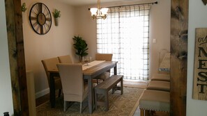 A dining area with a wooden table, two chairs, a bench, a clock, and a chandelier. - 2-bedroom Farm House with fenced back yard (Randallstown)