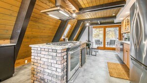 Cozinha moderna com ilha de tijolos, eletrodomésticos de aço inoxidável e vista para o exterior.