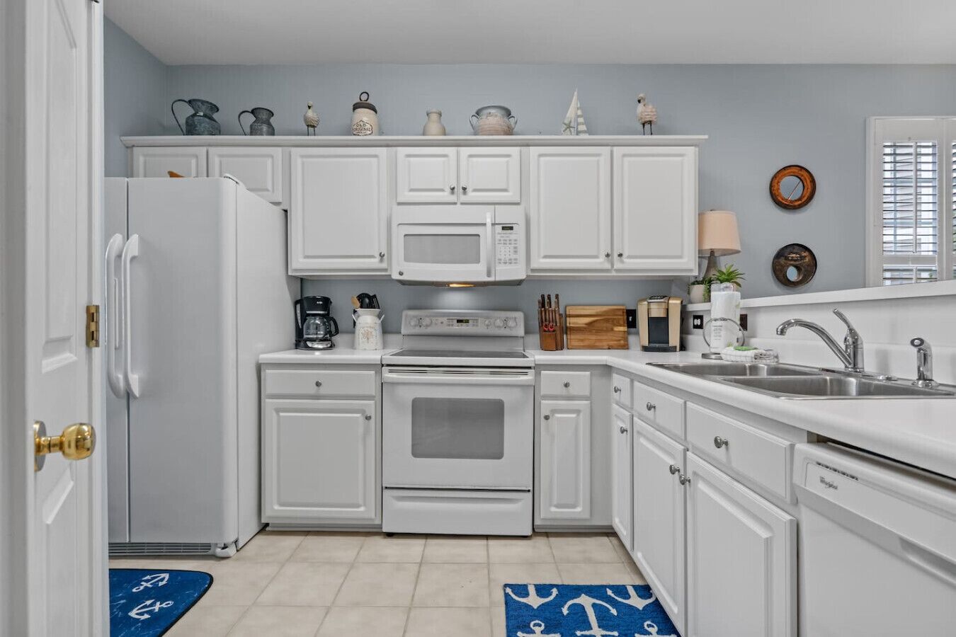 A kitchen with white cabinets, a refrigerator, a microwave, an oven, and a sink.