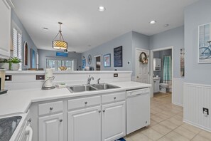 A modern kitchen with white cabinetry, a double sink, and a pendant light. - Sunset Beach Escape! (Sunset Beach)