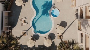 An aerial view of a swimming pool with surrounding lounge areas and palm trees. - Cavo Notos Beach Hotel (Lefkimmi)