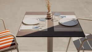 A table set for two with plates, cutlery, and a vase with dried flowers. - Cavo Notos Beach Hotel (Lefkimmi)