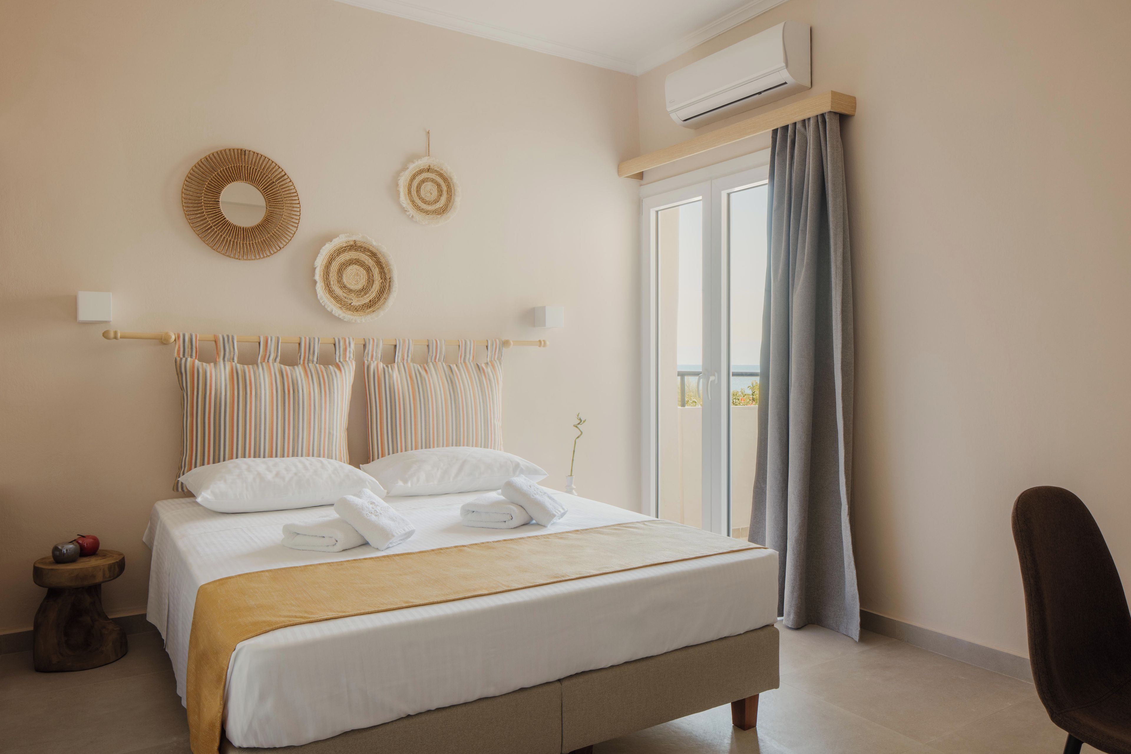 Ein Hotelzimmer mit einem Bett, einem Sessel, einem Fenster mit Vorhängen und einer Klimaanlage.