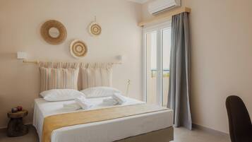 A hotel room with a bed, a chair, a window with curtains, and an air conditioning unit.