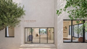 A modern hotel entrance with a minimalist design, featuring a staircase leading to a reception area. - Cavo Notos Beach Hotel (Lefkimmi)