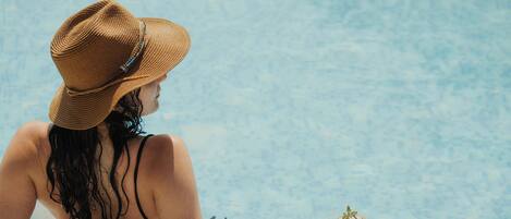 A person relaxing by a pool with a drink.