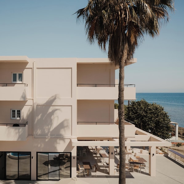 A multi-story hotel with balconies, a pool area, and a view of the sea. - Cavo Notos Beach Hotel (Lefkimmi)