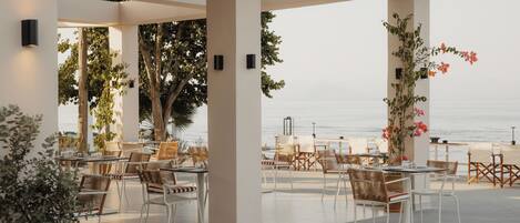 An outdoor seating area with tables and chairs, overlooking a body of water.