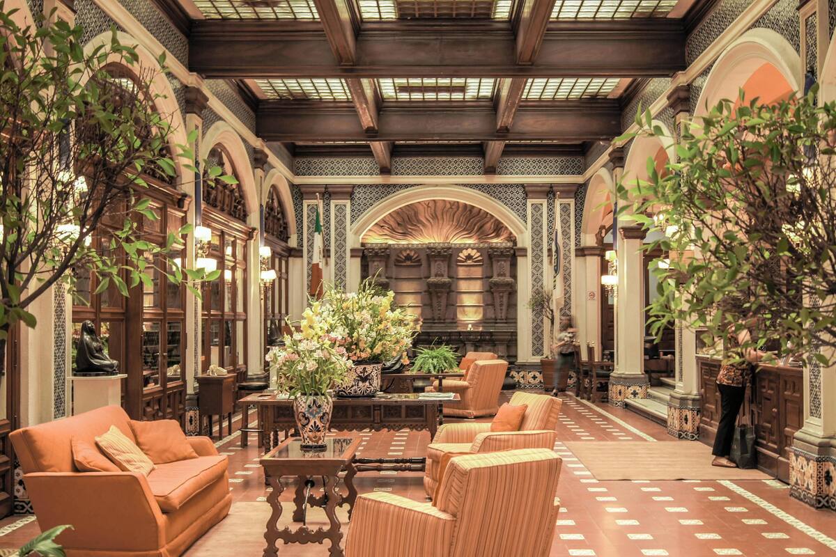 An interior with arched ceilings, wooden furniture, and a central floral arrangement.