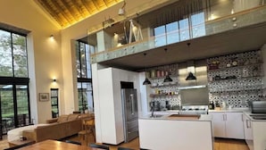 Una cocina moderna con una mesa de comedor de madera, una isla integrada y un techo alto con vigas a la vista.