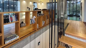 Un interior moderno con una escalera de madera, estanterías y un comedor.