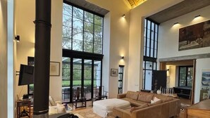 Amplia sala de estar con una gran estufa de madera negra, un sofá seccional color beige y una zona de comedor con mesa y sillas de madera.