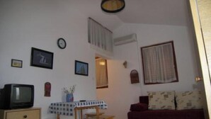 A living room with a television, a clock, and framed pictures on the wall. - Apartments Zlatko - Studio apartment with sea view A2 +1 (Prvic Luka)
