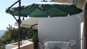 A patio with a table and chairs, an umbrella, and a view of the sea. - Apartments Zlatko - Studio apartment with sea view A2 +1 (Prvic Luka)