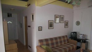 Ein Wohnzimmer mit einem karierten Sofa, einem Fernseher und gerahmten Bildern an der Wand.