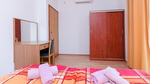 Ett hotellrum med en säng, ett skrivbord, en stol, en garderob och en luftkonditioneringsanläggning.