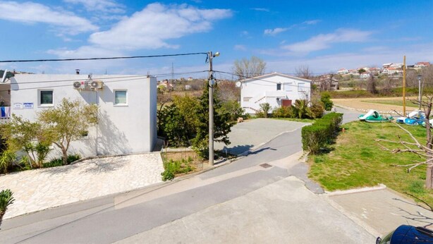 Una strada residenziale con case, cielo sereno e strada asfaltata.