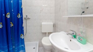 Un bagno con tenda doccia, servizi igienici, lavabo e dispenser di sapone.