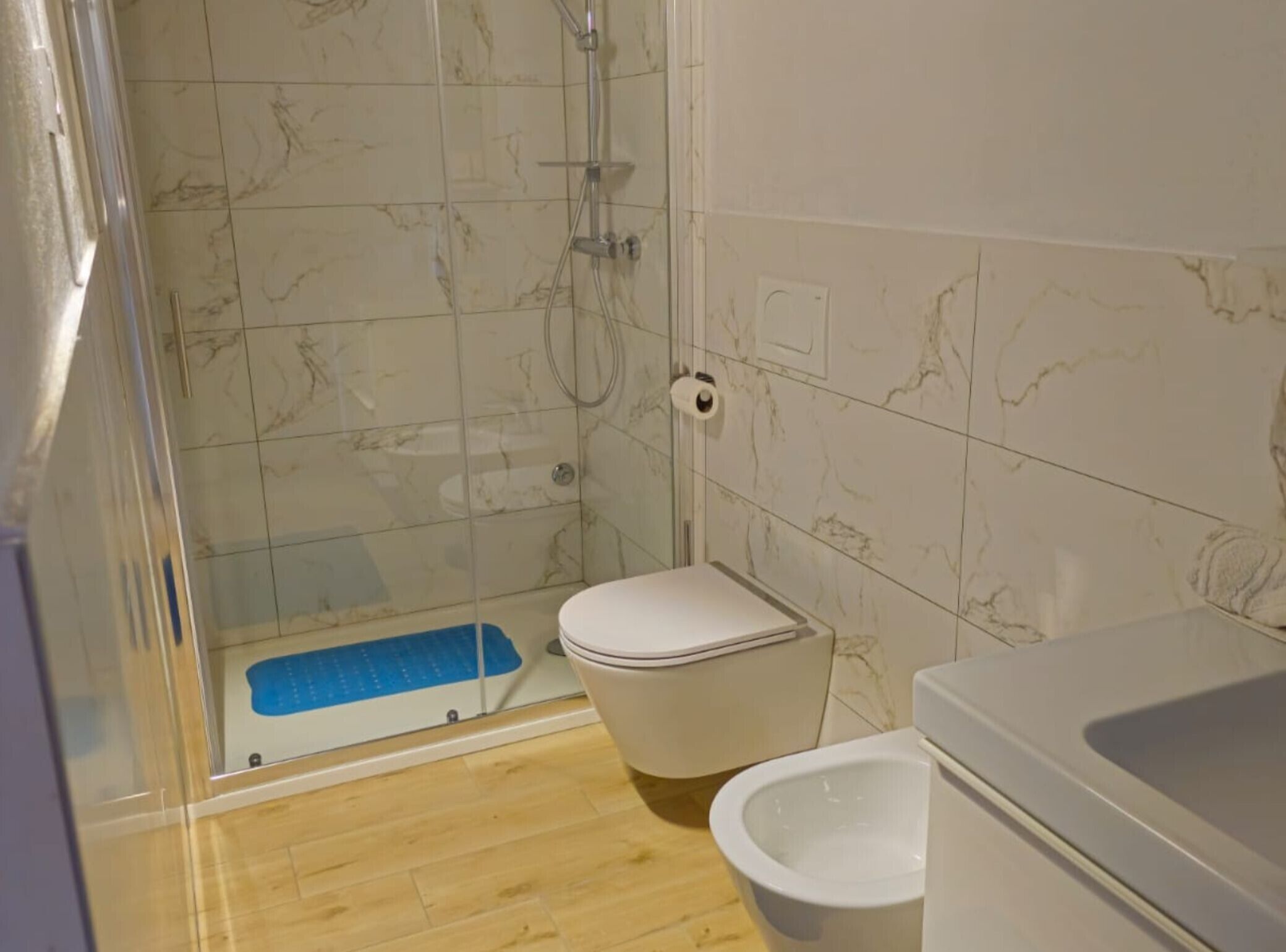 A bathroom with a shower, toilet, and bidet.