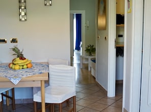 A dining area with a table set for two, a fruit bowl on the table, and a chair. There is a door leading to another room. - Apartments Ivo Rovinj - Two bedroom apartment (Tatjana) (Rovinj)