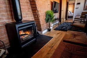 Ein gemütliches Wohnzimmer mit Kaminofen, Blumentopf und einer bequemen Sitzecke.