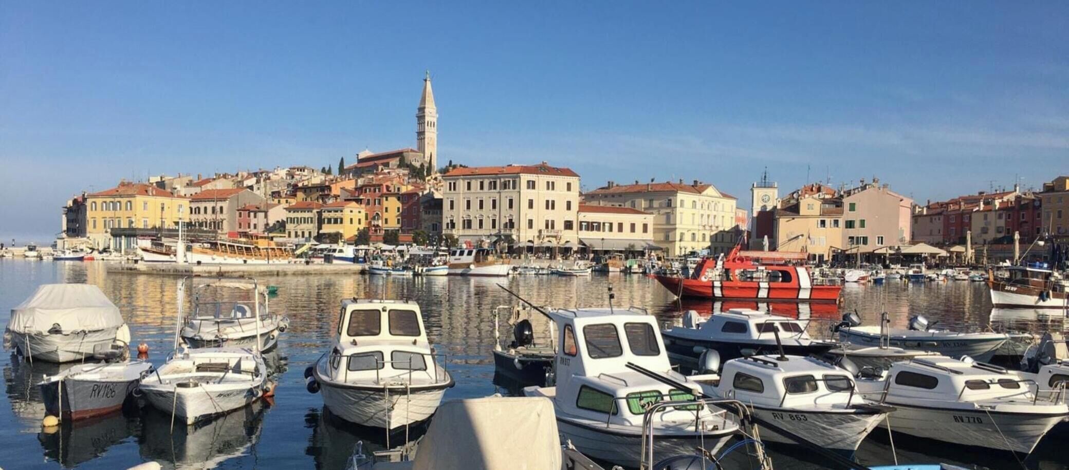 Un port esportiu amb embarcacions amarrades, una torre de l'ajuntament destacada i edificis històrics al fons.
