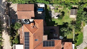 Una casa con techo inclinado, paneles solares, un garaje y un pequeño jardín.