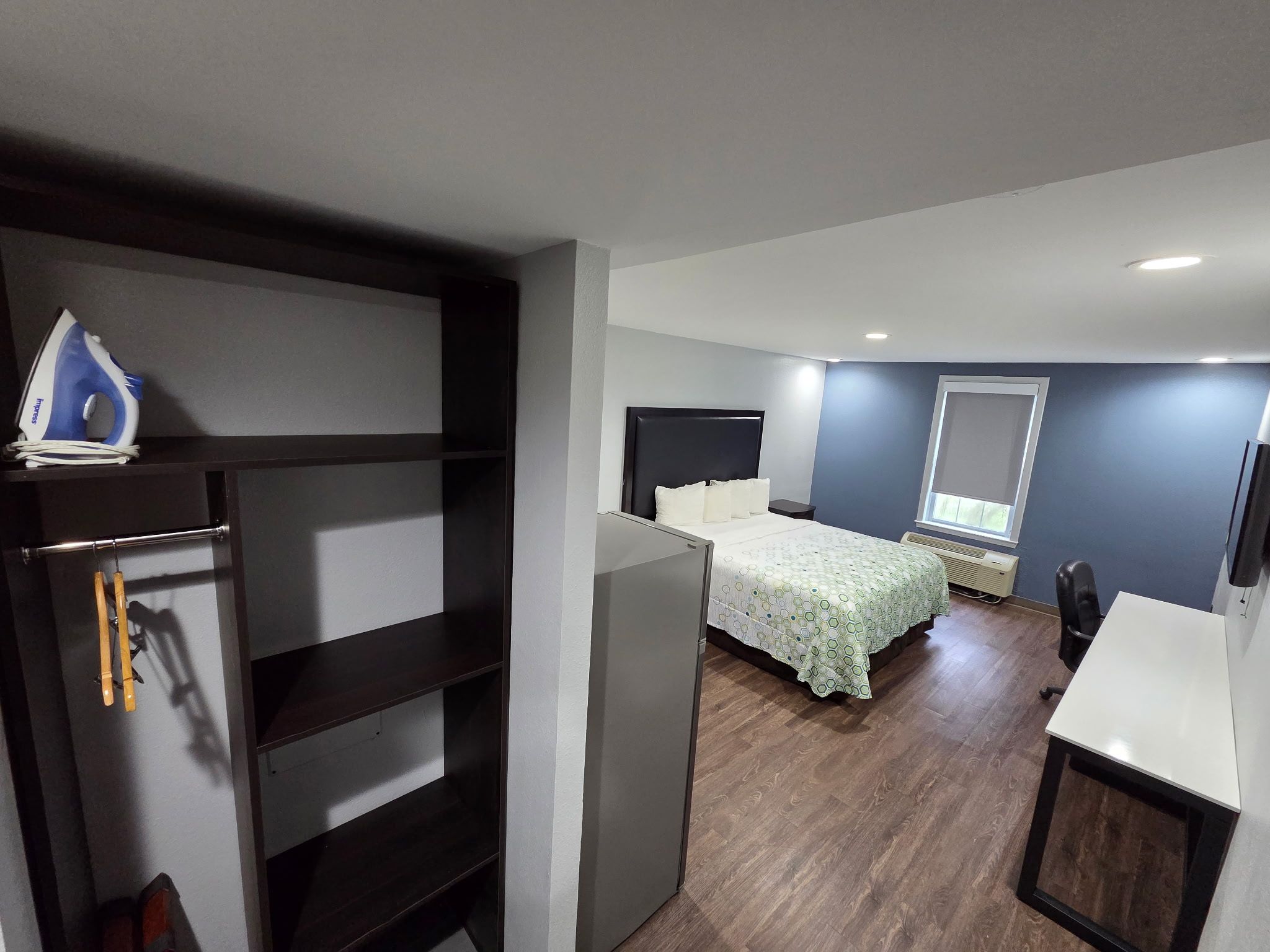 A compact bedroom with a bed, a desk, and a wardrobe.