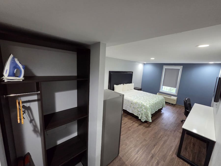 Quarto compacto com cama, escrivaninha e armário.