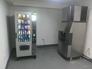 A vending machine and a stainless steel refrigerator in a room. - HomeTowne Studios by Red Roof Leesburg (Leesburg)