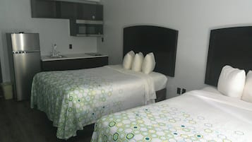 A hotel room with two beds, a kitchenette, and a small bathroom.