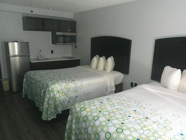 A hotel room with two beds, a kitchenette, and a small bathroom. - HomeTowne Studios by Red Roof Leesburg (Leesburg)