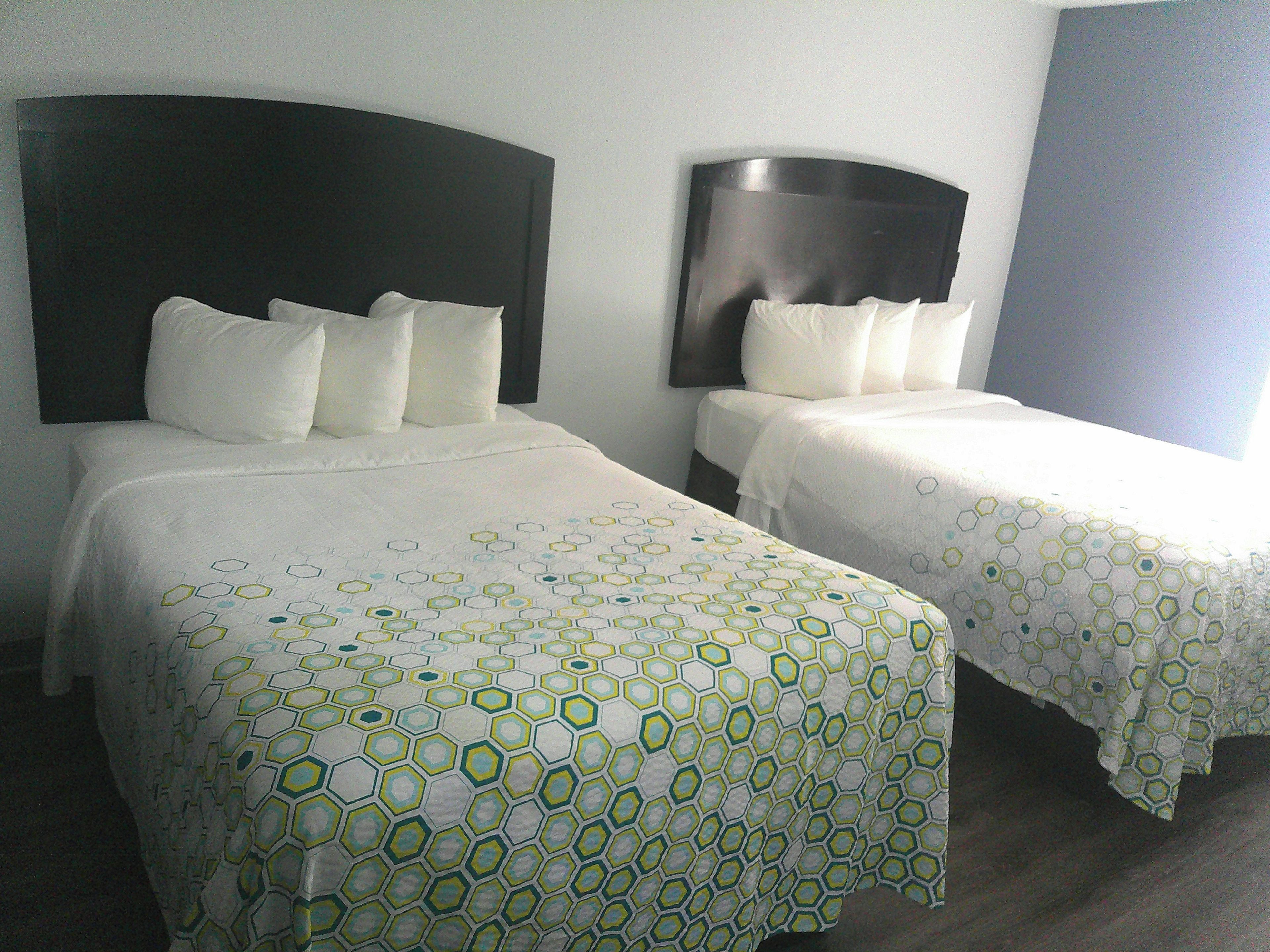 Two single beds with headboards, white bedding, and a geometric pattern on the bedspread.