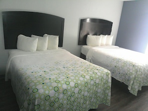 Dos camas individuales con cabeceras, ropa de cama blanca y un estampado geométrico en la colcha.