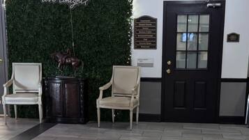 A reception area with a green wall, two chairs, a door, and a sign with a question.