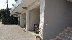 A building with a covered outdoor area, steps leading up to a door, and potted plants. - Apartments Rubić - Onebedroom Apartment with Loggia and SeaView (2) (Omis)