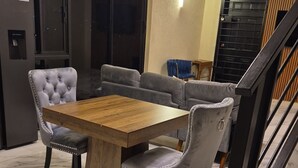 Ein Essbereich mit Holztisch, gepolsterten Stühlen, einer Couch und einer Treppe.