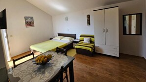 A bedroom with a bed, a wardrobe, a table with fruit, and a chair. - Apartments Rubić - TwoBedroom Apartment with Loggia and SeaView (5) (Omis)