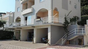 A multi-story residential building with balconies, a covered entrance, and a staircase leading to the upper floors. - Apartments Rubić - TwoBedroom Apartment with Loggia and SeaView (5) (Omis)