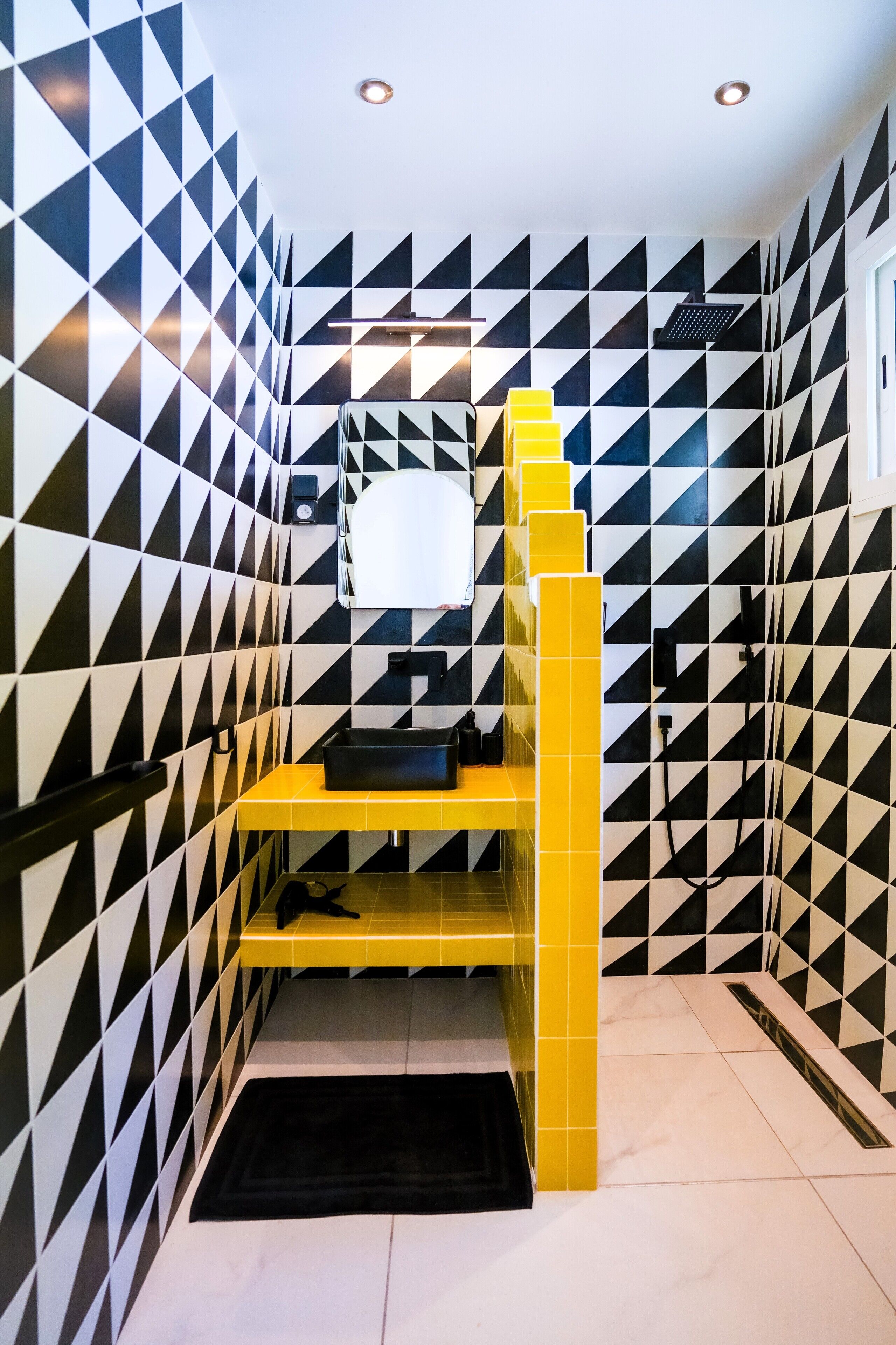 A room with black and white geometric patterned walls, a yellow bed frame, and a black rug on the floor.